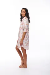 Vestido corto tipo camisero con estampado floral en tonos rosados, celestes y marrones. Tiene cuello camisero, mangas 3/4 abullonadas y cierre frontal con botones.