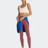 Calza deportiva New Balance Sleek High Rise, color rojo oscuro o rosado quemado, de tiro alto y corte ajustado. Presenta el logo NB reflectante en la parte trasera del muslo.