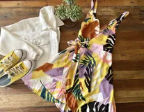 Vestido corto de fibrana con estampado abstracto en tonos amarillo, marrón, lila, verde y negro. Diseño cruzado con lazo en la cintura y breteles finos.