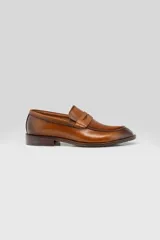 Mocasín de cuero color marrón tostado, diseño clásico de antifaz con costuras visibles en el empeine y suela de taco bajo.