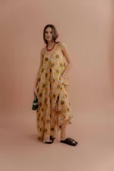 Vestido largo de tirantes finos, con escote en V y estampado de girasoles sobre fondo beige.