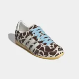 Championes Adidas modelo Japan con diseño de perfil bajo, exterior de cuero con acabado de pelo de poni y estampado animal print tipo jirafa. Presenta las icónicas tres tiras laterales en blanco, cordones en color celeste y suela de caucho en tono amarillento.