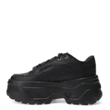Championes Puma modelo Karmen, de diseño urbano con plataforma elevada. Presentan un exterior sintético en color negro, con cordones al tono y detalles metálicos en los ojales superiores. Su suela robusta de goma proporciona estabilidad y un estilo moderno.