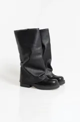 Botas de caña alta confeccionadas en ecocuero negro, con diseño holgado y suela plana con plataforma baja.