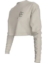 Remera cropped color beige de algodón, con cuello redondo y mangas largas. Presenta el logo de Calvin Klein Jeans estampado en el pecho.