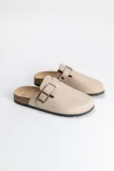 Zueco de estilo casual en color beige, con capellada de material sintético tipo gamuza, ajuste mediante hebilla metálica lateral y suela con detalle de corcho.