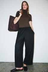 Pantalón de tiro medio con corte wide leg y cintura elástica ajustable. Presenta bolsillos laterales ocultos en las costuras y un diseño de pierna ancha con caída fluida.
