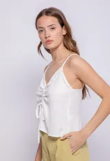 Top blanco de tirantes finos, escote en V con fruncido central ajustable mediante lazos.