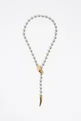 Collar de estilo lariat con cadena de bolas plateada y detalles dorados. Presenta un dije en forma de cabeza de serpiente que funciona como pasador y un terminal en punta que simula la cola. Está confeccionado principalmente en latón con acabado metálico bicolor.
