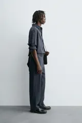 Pantalón de corte relaxed fit, con cintura ajustable, bolsillos delanteros y bolsillo trasero de plastrón. Presenta cierre frontal con cremallera y botón.