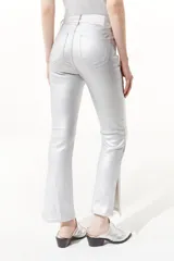 Pantalón jean plateado de tiro medio/alto con silueta levemente acampanada desde la rodilla y aberturas en los tobillos.