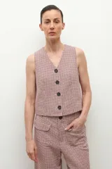 Chaleco de corte sastre con escote en V y cierre frontal con botones oscuros. Presenta un diseño de estampado a cuadros pequeños en tonos beige y rojizos.