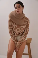 Sweater tejido con cuello alto voluminoso, manga larga y silueta holgada. Presenta un estampado animal print en tonos marrón y beige con hilo metalizado.