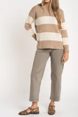Sweater de punto con diseño de rayas horizontales anchas, alternando color beige camel y blanco roto con motas de color. Presenta cuello redondo y puños y borde inferior acanalados.