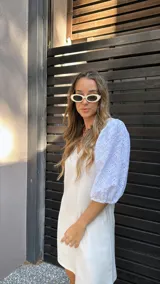 Vestido corto color crudo, con escote en V y mangas 3/4 abullonadas con detalles de calado.