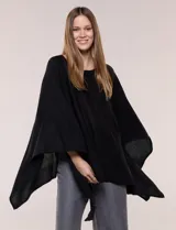 Poncho de calce holgado color marrón, confeccionado en tejido fino de punto suave, con cuello redondo y diseño de caídas laterales amplias de ruedo asimétrico.