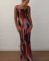 Vestido largo de microtul estampado con diseño abstracto en tonos marrones, naranjas y celestes. Tiene breteles finos y corte ajustado al cuerpo.
