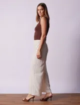 Pantalón largo de poliéster color beige con rayas verticales, pretina ancha elastizada en punto smock y pierna ancha.