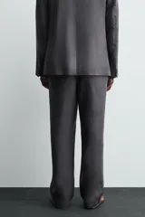 Pantalón de traje regular fit confeccionado en tejido de lino, con cierre frontal de cremallera y botón, bolsillos laterales y bolsillos traseros de vivo.