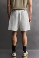 Pantalones cortos tipo jogger de corte relajado confeccionados en tejido de algodón. Presentan cintura elástica con cordón interior, bolsillos frontales en la cadera y un bolsillo trasero de plastrón.