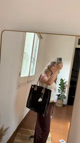 Tote bag de ecocuero color marrón oscuro con textura de cocodrilo, detalles de tachas en los laterales y asas de cuero marrón liso. Incluye un dije de guampa blanca colgando.