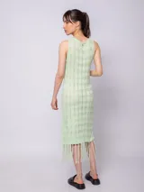 Vestido largo negro de tejido de punto con diseño de tramado y pequeños calados, sin mangas y con flecos en el ruedo.