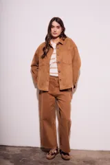 Sobrecamisa negra de estilo shacket, confeccionada en tejido de gamuza sintética. Presenta cuello camisero, cierre frontal de botones y dos bolsillos de parche con solapa en el pecho. El calce es oversize y las mangas son largas.