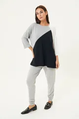 Remerón de manga tres cuartos con diseño de bloques de color en diagonal: gris claro en la parte superior izquierda, negro en la parte inferior derecha y blanco en la manga derecha. Posee cuello redondo y calce holgado.