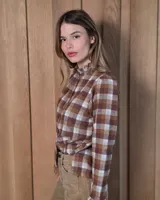 Camisa de algodón con estampado de rayas verticales finas, cuello alto con volados, cierre frontal con botones dobles y mangas largas con puños elásticos terminados en volados.