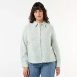 Camisa de manga larga color verde menta con estampado de cuadros vichy y delicado bordado inglés floral. Presenta cuello camisero clásico, cierre frontal abotonado oculto y terminaciones onduladas en el ruedo.