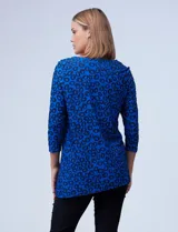Blusa azul con estampado de círculos negros, de tejido texturado con escote en V descentrado y aplique de aro metálico.