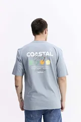 Remera de manga corta color verde militar, con escote redondo y un pequeño estampado frontal de formas geométricas de colores y texto manuscrito.