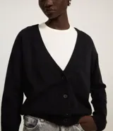 Cardigan corto de punto color marrón, con cuello en V, manga larga y cierre frontal con botones. Presenta puños y bajo acanalados.