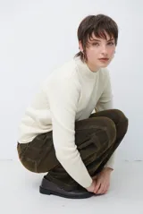 Polera de tejido de punto fino en color beige, con cuello alto y mangas largas con puños acanalados.