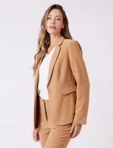 Blazer sastrero entallado color beige, con cuello de solapa, cierre frontal con un botón a tono y hombreras estructuradas. Presenta bolsillos laterales con solapa y forro interno.