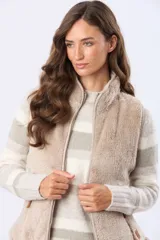 Chaleco de sherpa con cierre frontal, cuello alto y bolsillos laterales. Presenta detalles en cuero sintético en los tiradores de los cierres.