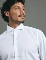 Camisa de vestir de manga larga, confeccionada en popelina fina de algodón, con cuello clásico y cierre frontal de botones.