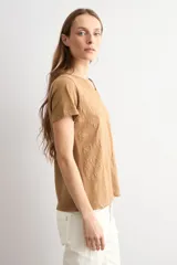 Remera marrón camel de manga corta, con cuello en V y diseño de estampado floral con relieve.