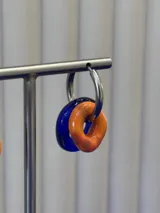 Aros de argolla plateada con dijes dobles de vidrio en forma de dona, uno en color azul y otro en color naranja.