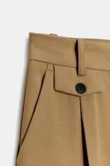 Pantalón de tiro medio con pinzas delanteras y pernera recta. Cuenta con bolsillos frontales, falsos bolsillos traseros de vivo y cierre frontal con cremallera, botón interior y ganchos.