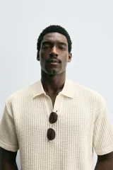 Polo de manga corta color marrón oscuro, confeccionado en tejido waffle de algodón, con cuello solapa y abertura frontal.