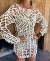 Vestido corto tejido a crochet color crudo, con mangas largas y diseño calado con patrón de telaraña.