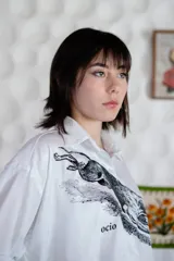 Camisa blanca de algodón con estampado de un galgo y la palabra "ocio" en el frente. Manga larga con puños y botones.