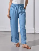 Pantalón celeste de lyocell, corte ancho, con pretina elastizada con lazo de ajuste, bolsillos verticales y ruedo desflecado.