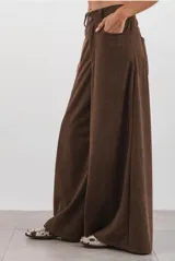 Pantalón de corte ancho confeccionado en corderoy color chocolate, con cintura alta, pasacintos y cierre frontal con botón.