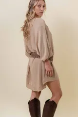 Cinturón de estilo urbano confeccionado en material símil gamuza color beige, con diseño de ojales metálicos y hebilla ovalada.