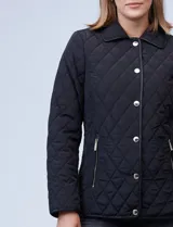 Campera capitoneada azul marino con cuello y ribetes en cuero marrón, marca Michael Kors. Abertura central con botones metálicos dorados, bolsillos verticales delanteros y logo metálico en el brazo.