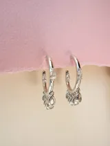 Aros tipo argolla dorados con siete circonias transparentes colgantes.