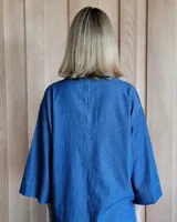 Blusón de denim oscuro con cuello camisero y escote en V, de corte holgado y mangas tres cuartos anchas.
