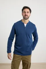 Remera de manga larga en tejido elastizado, color azul, con cuello tipo camisa, cartera con botones y detalles en eco gamuza en la base del cuello y la cartera.